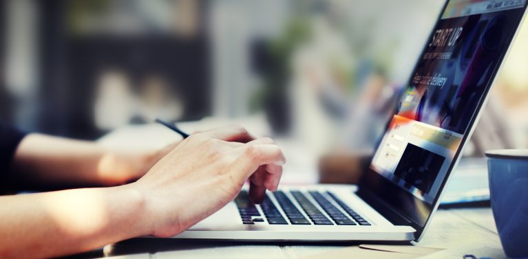 image of hands using a laptop in an office.