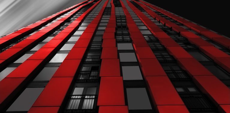 image of a red stripe building with black tinge glass windows. black blurred sky