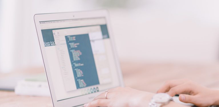 blurred image of a woman's hands typing on a computer.