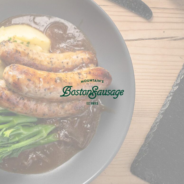 A photo of boston sausages and mash with the boston sausage logo in green in the centre of the photo